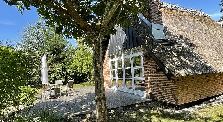 Charmerende sommerhus med stråtag tæt ved vandet