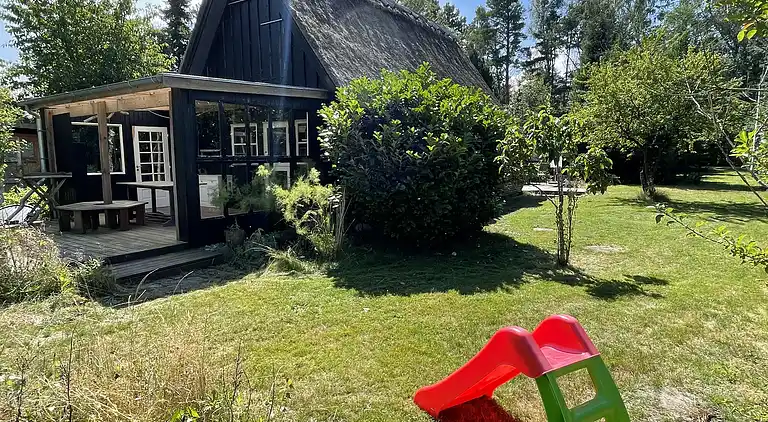 Charmerende sommerhus med stråtag tæt ved vandet